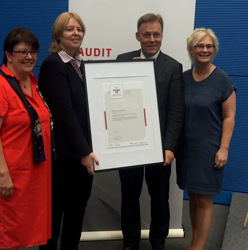 Vier Personen halten bei einer Zertifikatsübergabe gemeinsam eine gerahmte Urkunde des audit berufundfamilie